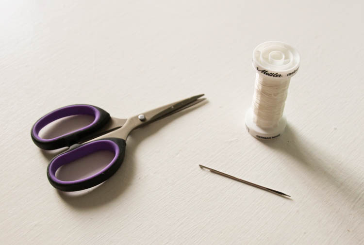 A needle, thread, and scissors on the counter.
